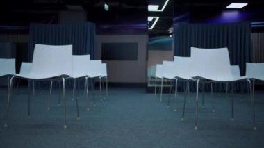 Beyaz sandalyeli ve aydınlanmış modern konferans salonu.