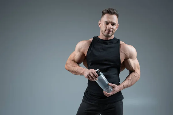 Αθλητής άνθρωπος ή bodybuilder με μπουκάλι νερό σε γκρι φόντο με αντίγραφο χώρο — Φωτογραφία Αρχείου