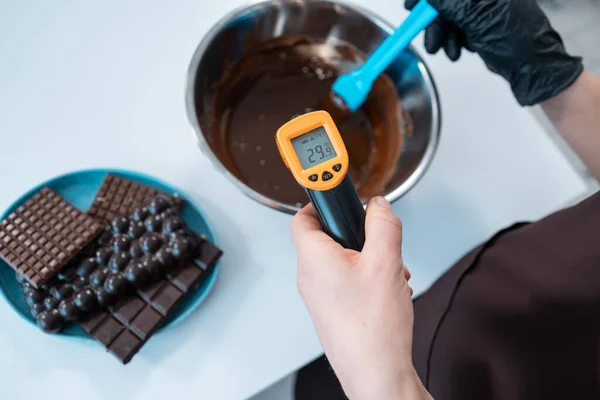 Close-up da temperatura de medição feminina de chocolate derretido com pirômetro — Fotografia de Stock