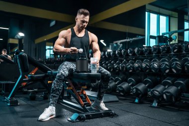 Sporcu protein kokteyli hazırlıyor ya da spor malzemesi kullanıyor.