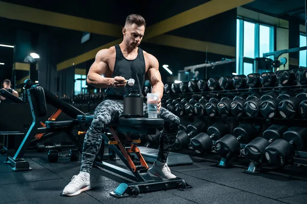 Idrettsutøver som tilbereder proteincocktail eller bruker sportskosttilskudd i gym – stockfoto