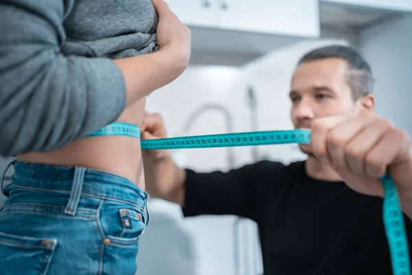 Fitness homem nutricionista medir cintura mulher com fita métrica centímetro — Fotografia de Stock