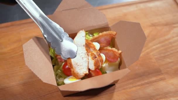 Close-up de cozinheiro chef mão em luvas médicas colocar salada fresca em recipiente de comida — Vídeo de Stock