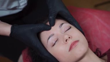 Kozmetikçide gençleşen kafa ya da yüz masajı prosedürü üzerine çalışan güzel bir kadın.