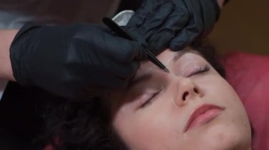 Güzellik uzmanındaki kadının kaş düzeltme prosedürünü cımbızla kapat.