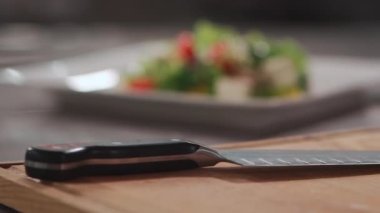 Kare beyaz tabakta taze Yunan salatası ve baharatı yakın plan.