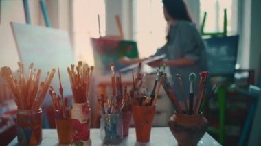 Fırça ve yağlı boyayla çizim yapan kadın sanatçı.