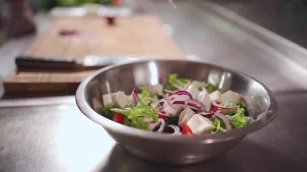 Nahaufnahme von Koch Koch Hand in medizinische Handschuhe legte rote Zwiebel in frischem griechischen Salat — Stockvideo
