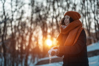 Güzel, mutlu bir bayan karla oynuyor ve kış parkında eğleniyor.