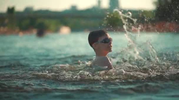 戴着水杯的活泼的小孩在湖中、河里或海里游泳，玩飞溅游戏 — 图库视频影像