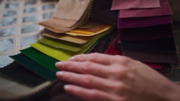 Tekstil galerisindeki renk paletinden kumaş seçen kadın ellerinin yakın çekimi — Stok video