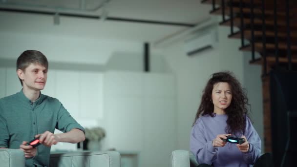 Щаслива пара грає в відеогру з контролером на ігровій станції вдома — стокове відео