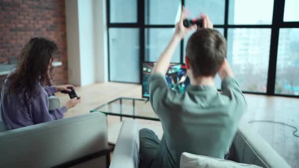 Щаслива пара грає в відеогру з контролером на ігровій станції вдома — стокове відео