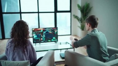 Mutlu çift evde Playstation konsolunda oyun oynuyorlar.