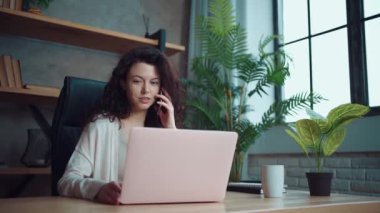 Bilgisayarla çalışan ve cep telefonuyla konuşan neşeli bayan yönetici.