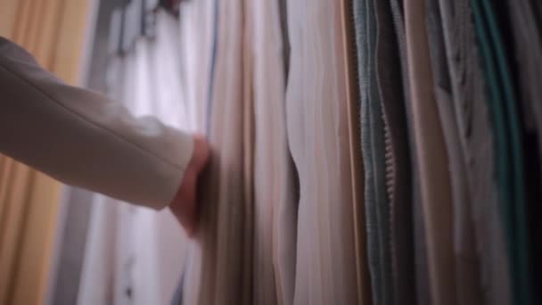 Close-up van vrouwelijke hand kiezen stof doek voor gordijn in showroom of winkel — Stockvideo