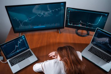 Yeni başlayan yorgun kadın tüccar iş yerinde hisse senedi grafiğiyle monitörün yanında uyuyor.