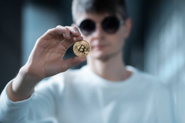 Erkek yatırımcının elinde altın bitcoin ya da kripto para tutarken yakın plan