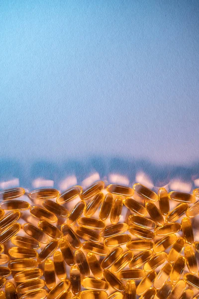 Handful of golden fish oil capsules omega 3 vitamins on purple background — Stock Photo, Image