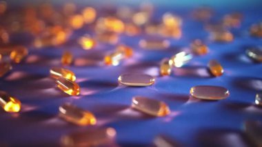 Mavi arka planda bir avuç altın balık yağı kapsülü Omega 3 vitamini