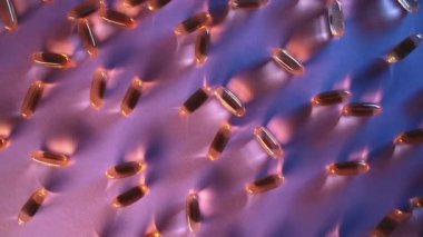 sağlıklı altın balık yağı kapsülleri Omega 3 vitaminleri mor arka planda