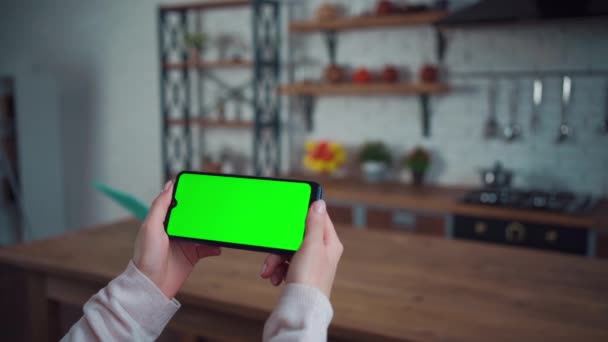 Detailní záběr ženské ruky pomocí smartphone se zelenou obrazovkou mockup v domácí kuchyni — Stock video