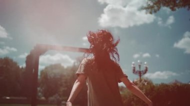 Su püskürtme çerçevesinde güzel bir kadın kamu parkında, ağır çekimde.