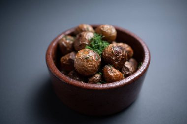 Kil kasede siyah arka planda otlu kızarmış patatesleri yakın.