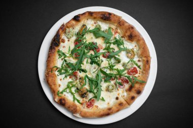 Siyah zemin üzerinde karides, midye ve roka olan deniz ürünleri pizzası manzarası.