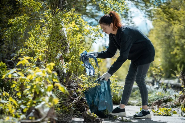 Mujer voluntaria limpiando el parque y el árbol de la basura de plástico con bolsa de basura — Foto de Stock