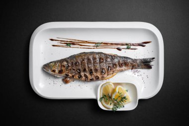 Siyah arka planda limonlu ızgara doldurulmuş balığın tamamını kapat.