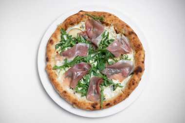 Beyaz arka planda prosciutto, roka ve peynirli lezzetli pizzanın üst görüntüsü.