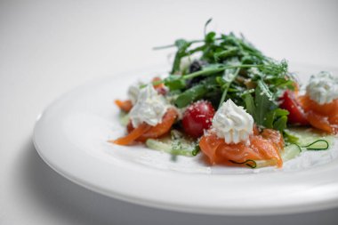 Beyaz arka planda tuzlanmış somon, krem peynir ya da roka ile yakın plan salata