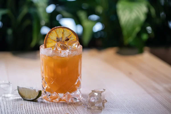 Limonádé üvegben vagy frissítő ital narancslével, lime-mal és jéggel az asztalon — Stock Fotó