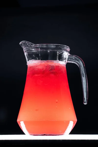 Limonade aux baies rouges ou boisson aux fraises avec glace dans une cruche en verre sur fond noir — Photo