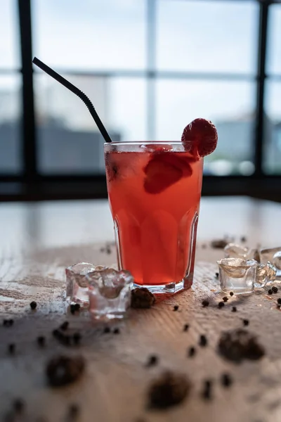 Detailní záběr červeného limonádového nápoje s jahodami ve skle a ledem na dřevěném stole — Stock fotografie