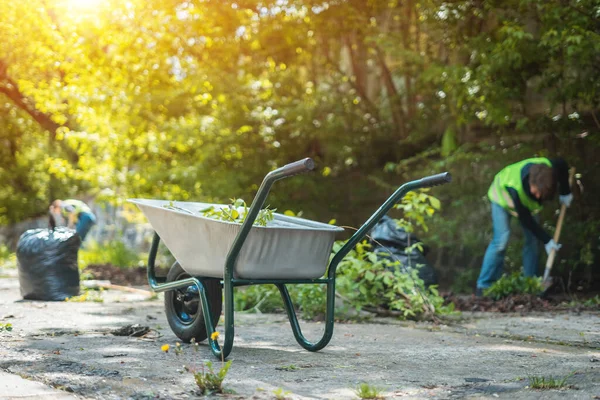 Baharda yapraklı el arabası ya da güneşli bir günde şehir parkını temizlemek. — Stok fotoğraf