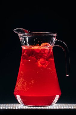 Serinletici limonata köpüklü cam sürahi ve siyah arka planda buz.