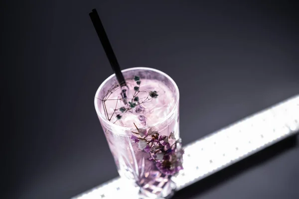 Luxus-Cocktailgetränk Violet Fizz mit Blumendekoration auf schwarzem Hintergrund — Stockfoto