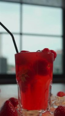 Kırmızı limonata içeceğiyle birlikte düşen çilek bardağına yakın plan.