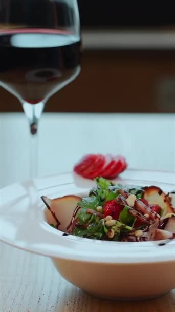 Zbliżenie sałatki z rukolą, szynką mięsną i truskawką lub kieliszkiem wina na stole — Wideo stockowe