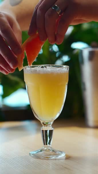 Decorare a mano cocktail tropicale giallo con fetta di pompelmo in calice di vetro — Video Stock