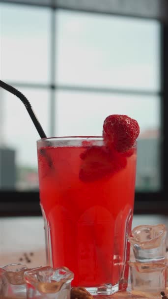 Närbild av fallande jordgubbar i glas med uppfriskande röd lemonad dryck — Stockvideo