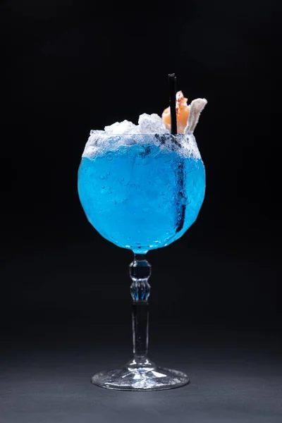Роскошный коктейль из синего алкоголя, украшенный креветками в стекле на черном фоне — стоковое фото