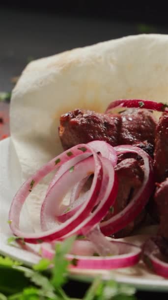 Zbliżenie przygotowanego szaszłyka lub grillowanego mięsa na picie z cebulą i zielenią — Wideo stockowe