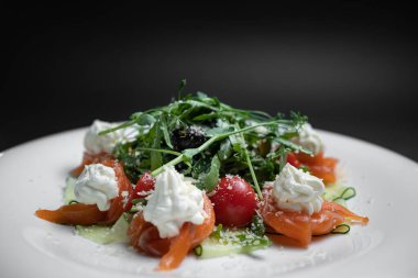 Siyah arka planda tuzlanmış somon, krem peynir ya da roka ile yakın plan salata