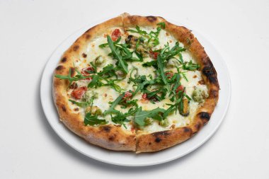 Beyaz arka planda karides, midye ve roka içeren deniz ürünleri pizzası.