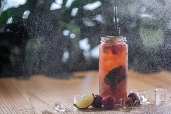 Aardbeienlimonade drinken met munt en ijs in glazen fles onder water spray — Stockfoto