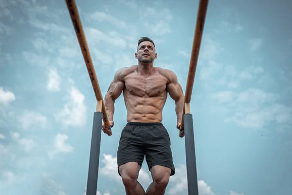 Atractivo atleta muscular hombre o culturista tire hacia arriba y el ejercicio al aire libre — Foto de Stock
