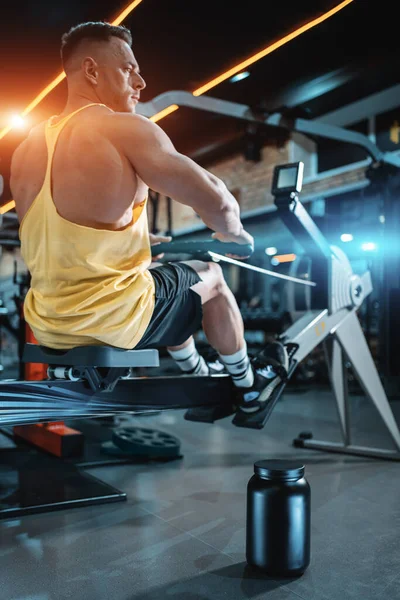 Protein whey powder in black container and bodybuilder male exercising in gym — Stock Photo, Image